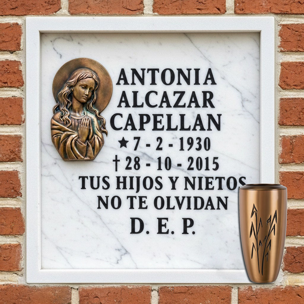 Lápida de columbario en mármol con imagen de la Virgen María en relieve y jarrón de bronce, con inscripción conmemorativa