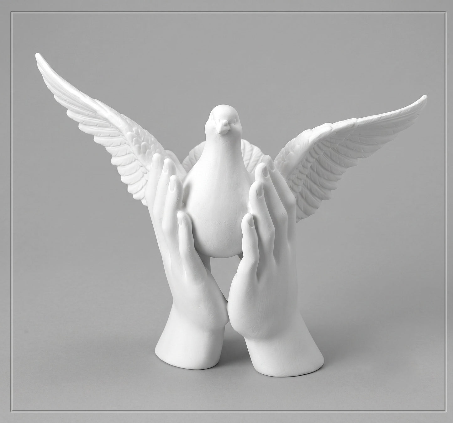 Escultura blanca de mármol sintético con dos manos alzando una paloma con las alas extendidas, modelo Ref 6592