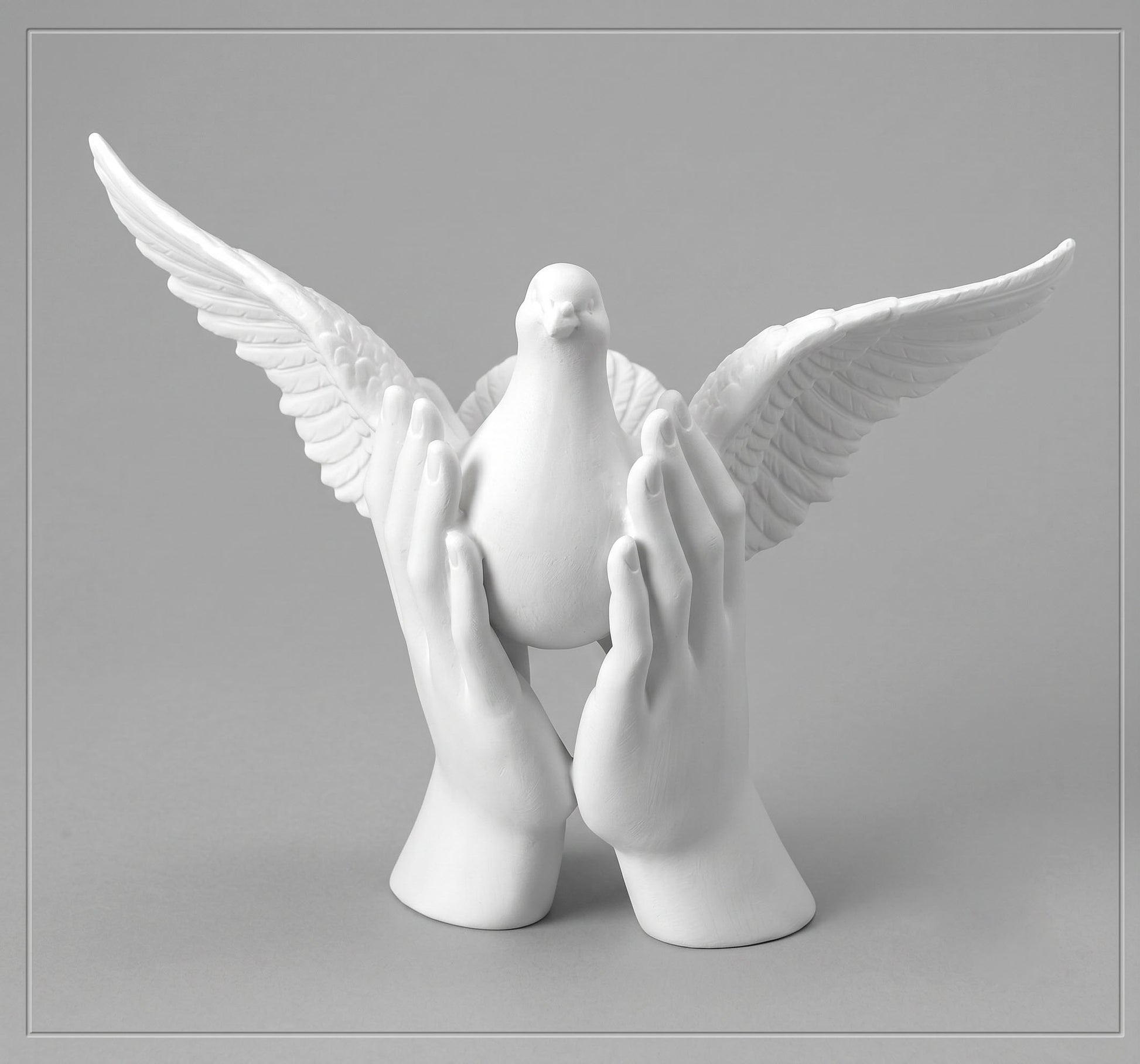 Escultura blanca de mármol sintético con dos manos alzando una paloma con las alas extendidas, modelo Ref 6592