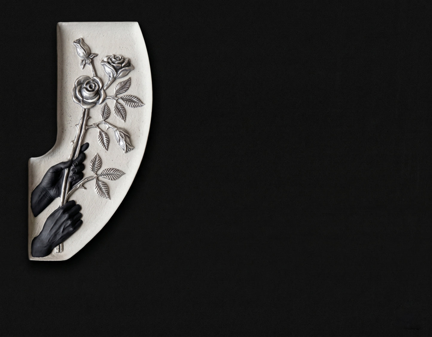 Lápida de nicho en granito negro con manos sosteniendo una rama de rosas talladas. Trabajo artesanal, gran durabilidad y acabado elegante para cementerios.
